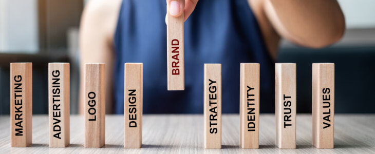 Businesswoman hand placing or pulling wooden Dominoes with BRAND text