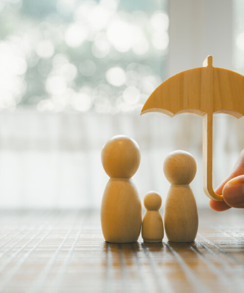 Parent and child model holding an umbrella on a wooden table, concept of health insurance, life and savings insurance